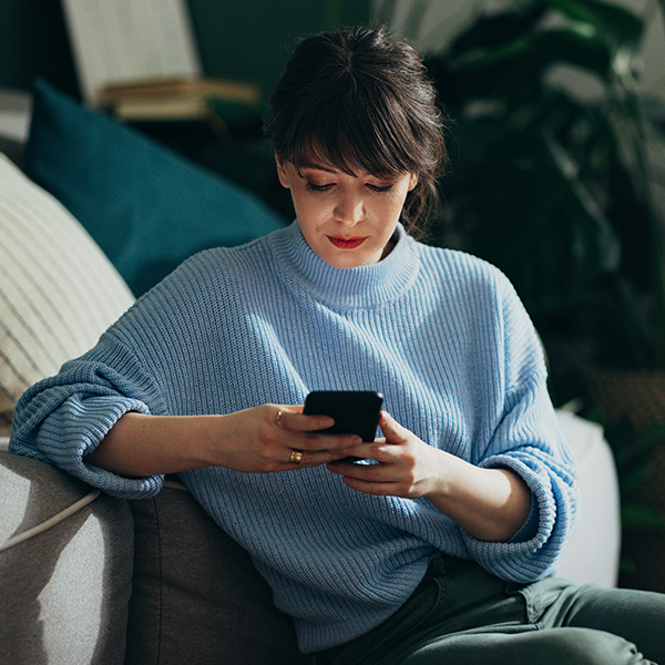 Woman sitting on couch looking at phone