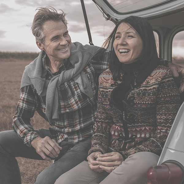 Man and woman sitting on tailgate laughing 